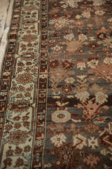 Intricate floral patterns on the border and abrashed charcoal field of a distressed Malayer runner.
