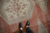 Worn texture of a distressed vintage Veece carpet showing brick red and seafoam green patterns.