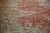 Detailed view of the rug's worn pile showing the brick red and seafoam green knot heads.