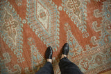 Worn texture and hook motifs of a vintage Veece carpet in rust, blue, and ivory.