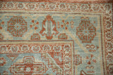 Worn texture and floral border detail on a distressed Persian Veece carpet in rust red and powder blue.
