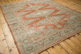 An angled view of the vintage Persian Veece carpet showing the time-softened texture and geometric patterns.