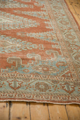 Angled perspective on the distressed texture and floral border of a vintage Veece carpet.