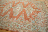 Corner view showing the distressed texture and floral border of a vintage Persian Veece carpet.