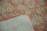 Vintage distressed Sarouk carpet with a corner folded back to show its hand-knotted foundation.