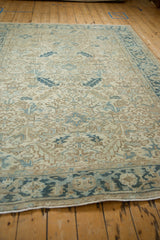 Low angle view across the time-softened pile of a distressed Heriz rug with blue geometric details.
