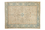 Distressed vintage Heriz carpet with a geometric floral medallion in ivory, dusty blue, and sand.
