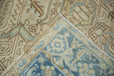 Folded corner of a distressed Heriz carpet, revealing its hand-knotted weave and intact side cord selvage.