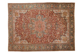 Vintage distressed Ahar carpet with a starburst medallion on a cherry red field with floral details in teal, blush, and ivory.