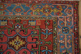 Vintage Karaja rug corner, brick red field with pinwheel florals, blue elongated Samovar border.