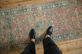 Distressed Sarouk runner, faded ruby red and dusty teal floral sprays with even pile wear.
