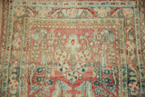 Distressed Sarouk rug, worn pile showcasing floral sprays and arabesque border in ruby, dusty teal, ivory.