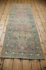 Distressed Persian Sarouk runner: ruby floral sprays, dusty teal arabesque border, and soft patina.