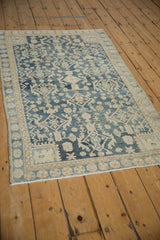 Distressed vintage Hamadan rug corner, dusty navy blue pinwheel border, ivory pattern.