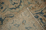 Distressed vintage Meshed carpet folded corner showing hand-knotted foundation and faded blue design.