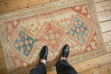 At-foot perspective of a vintage distressed Shiraz rug with geometric blue and ruby red medallions.