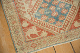 Corner detail of a vintage Shiraz rug showing its ruby red animal and geometric border.