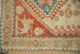 Corner of a distressed vintage Shiraz rug showing a ruby red animal motif and even, low pile.