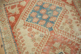 A stylized animal on the prowl motif within the worn, ruby red corner of a vintage Shiraz rug.