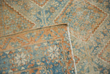 Distressed Afshar rug corner reveals worn blue, tangerine, ivory patterns and fringe.