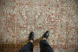 A person's perspective of the distressed, low-pile texture on a vintage Heriz carpet.
