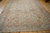 Angled view of a distressed Heriz carpet's allover geometric design and soft powder blue border.