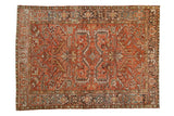 Vintage distressed Heriz carpet with a bold geometric medallion in faded madder red, dusty teal, and charcoal hues.