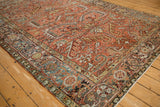 Angled view of the distressed Heriz carpet corner highlighting the geometric border and red field.