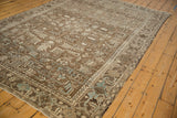 Angled view of a vintage Mehrivan carpet, displaying its distressed texture and geometric Turtle Samovar border motif.