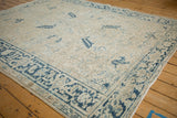 Angled view of a distressed Mehrivan carpet showing its low-pile texture and geometric blue border.
