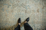 Textured surface of a distressed vintage Heriz rug with ivory, blue, and brown geometric florals.