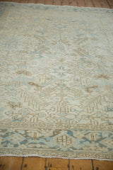 Vintage distressed Heriz carpet's worn pile, geometric motifs in soft ivory, blue, and beige.