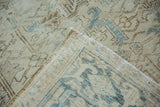 Folded corner of distressed vintage Heriz carpet, showing worn pile and faded geometric motifs.