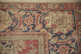 Distressed Sparta rug corner, displaying worn red, navy, and beige palmette and vine motifs.