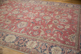 Distressed Sparta rug's raspberry field with cream palmettes, navy vines, and floral border.