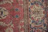 Close-up of distressed Sparta carpet showing faded raspberry, navy, beige palmettes and border.