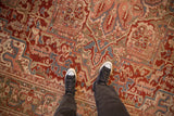 Worn pile of a distressed Heriz carpet revealing intricate geometric patterns in red, blue, and olive.