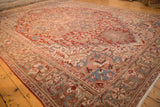 Low angle view of a vintage Heriz carpet showing its cherry red geometric field and olive green border.