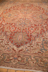 Angled view along the cherry red field of a distressed Heriz carpet with geometric patterns.