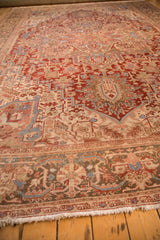 A low angle perspective showing the distressed, low-pile texture of a vintage Persian Heriz carpet.