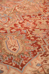 Low-angle view of a vintage Heriz carpet's textured, low pile, detailing its geometric patterns in red, sky blue, and olive.