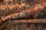 A fold in the vintage Heriz carpet reveals the low, distressed pile and hand-knotted texture.