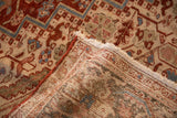 The hand-knotted back of a vintage Heriz carpet, showing the weave and fringe at a folded corner.