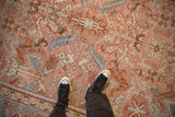 Overhead detail of a distressed Heriz carpet's low pile, with scrolled leaves and arabesques in blush and slate blue.
