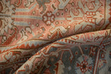 The low, hand-knotted pile of a distressed Heriz carpet in dusty blush, cream, and slate blue tones.