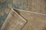 Corner of a distressed Tabriz carpet folded back to show its hand-knotted construction.