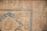Corner detail of a distressed Malayer rug showing even wear and a sky blue meandering vine border.
