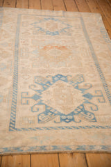 A vintage Persian Malayer rug from a low angle, showing the time-softened blue and ivory geometric design.