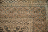 Corner of Antique Distressed Tabriz carpet, showing worn pile, lattice panels, and floral guls.
