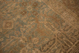 Textured blue-green and brown floral guls on a distressed Antique Tabriz carpet.